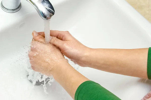 Hands with soap are washed under the tap with water. Clean from infection and dirt and virus. At home or in the hospital ablution office.