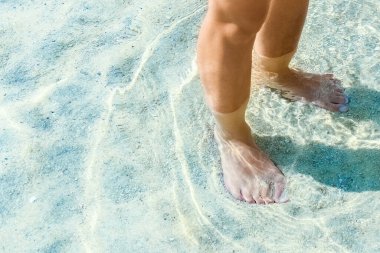 Yunan Denizi kıyısındaki kumların üzerinde güzel bacaklar