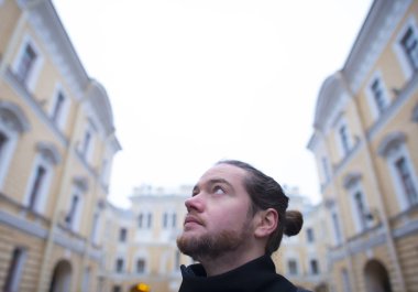 Sakallı adam yüksek binaların görünüyor.