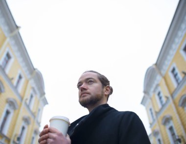 Sakallı adam yüksek binaların görünüyor.