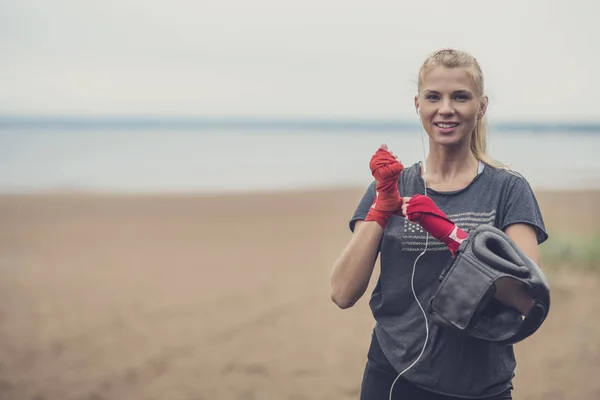 Deportiva sonriente aplicando sus muñequeras antes de comenzar su —  Fotos de Stock