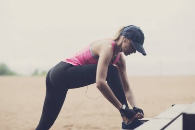 İnce sarışın koşucu kız onun ayakkabı bağlama