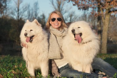 İki samoyed köpek ile gülümseyen genç kadın