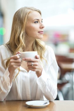 Bir kafede otururken ve sabahları kahve içme genç kadın