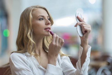 Çekici genç kadın kompakt ayna ve deliğe bakan