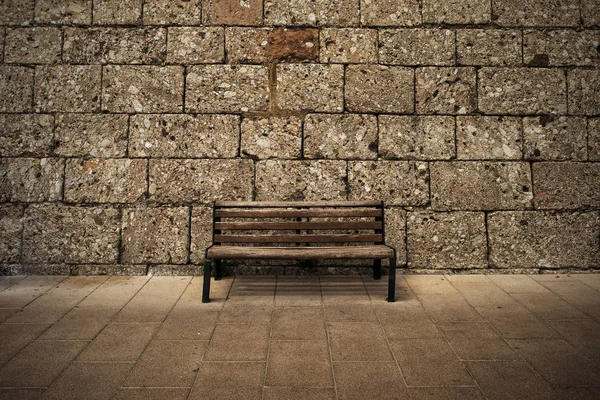 Wooden bench at the wall - dark brown grunge background — Stock Photo, Image