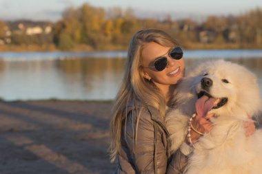 Genç kadın ile onun samoyed köpek parkta oynarken