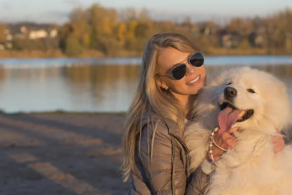在公园玩的年轻女子与她的萨摩耶狗 免版税图库图片