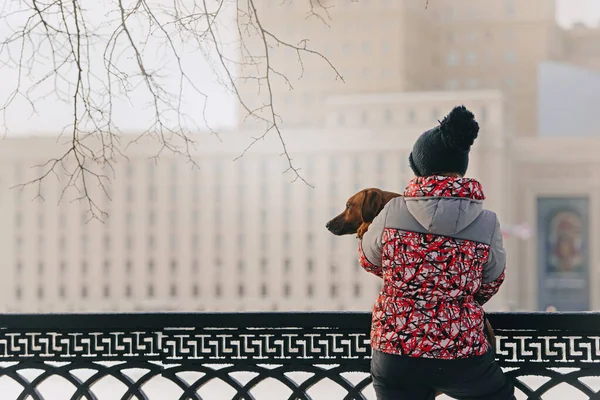 Woman holding her dog in her arms outdoors in winter — Stock Photo, Image