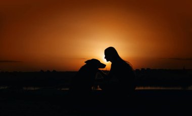 kız ve köpek siluetleri gün batımında dışarıda