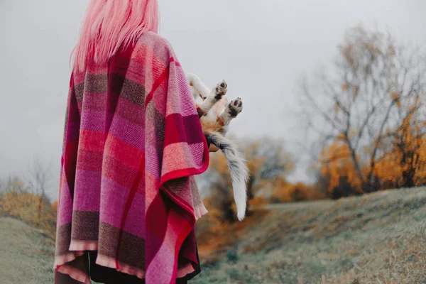 Woman with pink hair holding her puppy outdoors, rear view — Stock Photo, Image