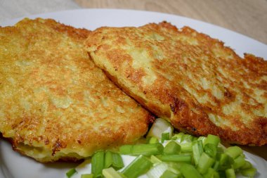 Ekşi krema ve bir plaka üzerinde yeşil soğan ile ev yapımı kızarmış patates pancakes