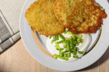Ekşi krema ve bir plaka üzerinde yeşil soğan ile ev yapımı kızarmış patates pancakes