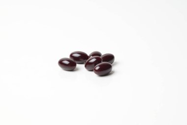 Group of astaxanthin capsules scattered on a white background.