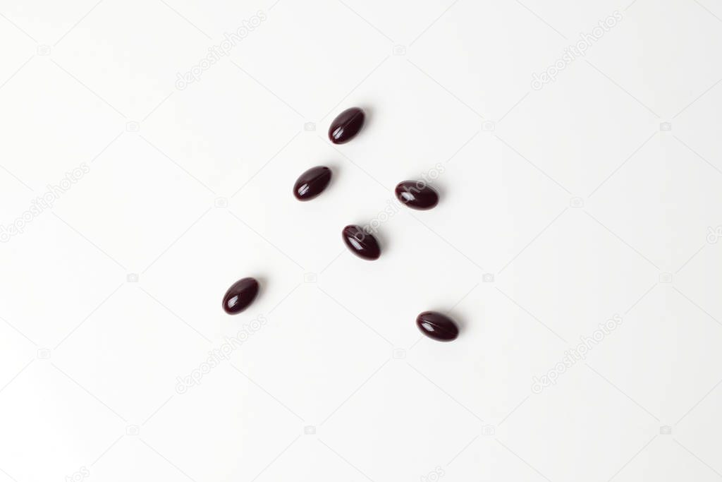 Astaxanthin capsules scattered on a white background. Top view.