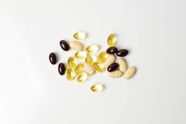 Beyaz arka planda dağınık haplar. Astaxanthin, balık yağı ve vitamin. Üst görünüm.