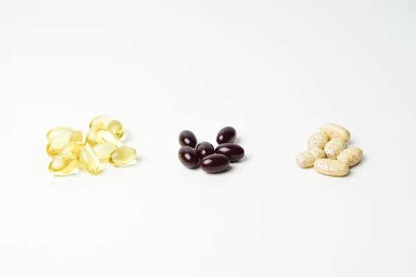 Üç paket multivitamin, balık yağı ve ince bir yağ. Keto-karotenoid ortada. Beyaz arka plan. Yakın plan..