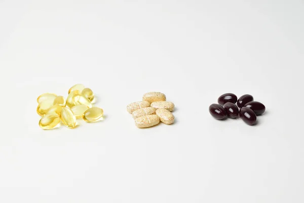 Üç paket multivitamin, balık yağı ve ince bir yağ. Vitaminler ortada. Beyaz arka plan. Yakın plan..