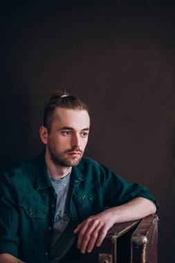 Karanlık bir arka planda erkek portresi. Saçları tomar tomar dökülen adam. Fotoğraf seyahat ve rahatlama arzusunu yansıtıyor..