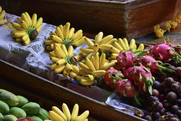 Teknedeki tropikal meyvelerin güzel bileşimi. Sarı muz ve ejderha meyveleri. Yüzen pazar, Tayland 