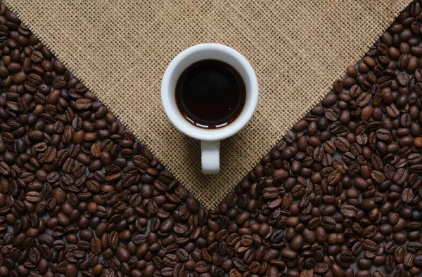 Een Witte Kop Koffie Een Achtergrond Van Koffiebonen Grove Jute — Stockfoto