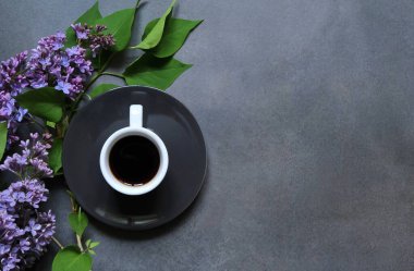 Beyaz kupa, güzel bir leylak arka planına karşı yeni demlenmiş sade kahve. Kahve bileşimi. 