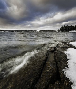 kar ve kayalıklarla göl kenarında