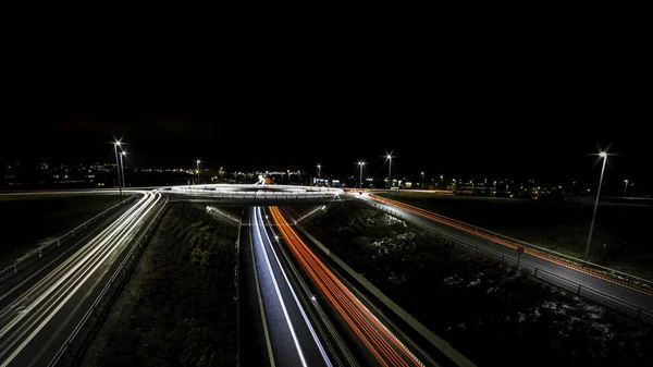 Lichtwege für Autos, die an einem Kreisverkehr und Straßenrändern vorbeifahren — Stockfoto