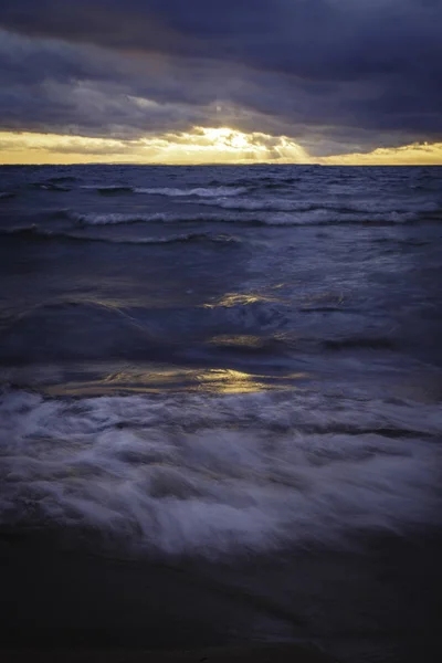 gün batımında kumlu bir plaj üzerine acele dalgalar