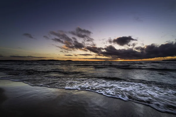 gün batımında kumlu bir plaj üzerine acele dalgalar