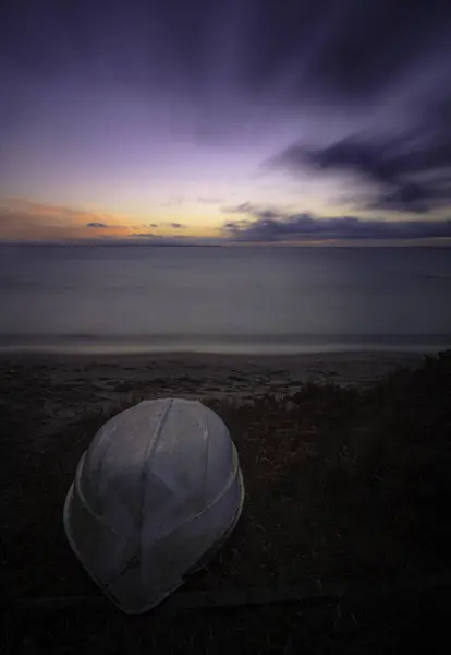 Boot liggen kant op een strand bij zonsondergang — Stockfoto
