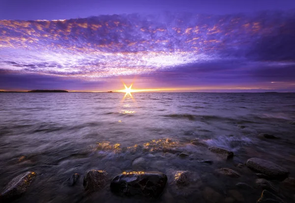 लहरों के साथ एक चट्टान समुद्र तट पर सूर्यास्त — स्टॉक फ़ोटो, इमेज