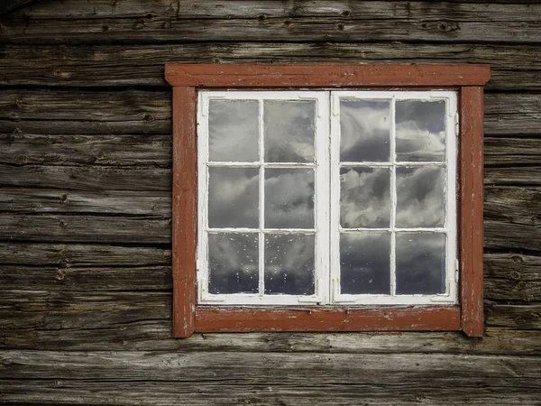 Holzhäuser mit roten Fenstern und Reflexionen aus den Wolken i — Stockfoto