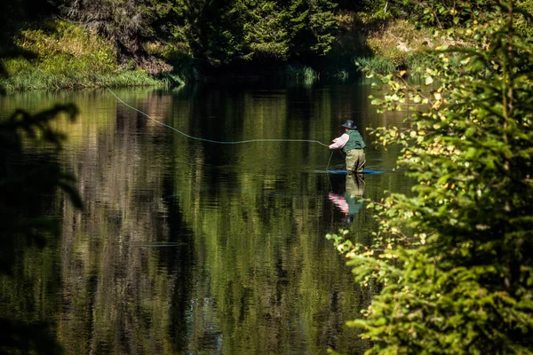 Mannen flugfiske stående i floden, med grön väst. — Stockfoto
