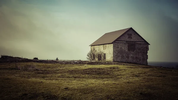 Altes Steinhaus mit Gras im Vordergrund und blauem Himmel im Bac — Stockfoto