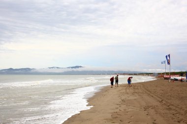 Grosseto, 13 Eylül 2017, İtalya, fırtınadan sonra kumsalda yürüyen üç adam