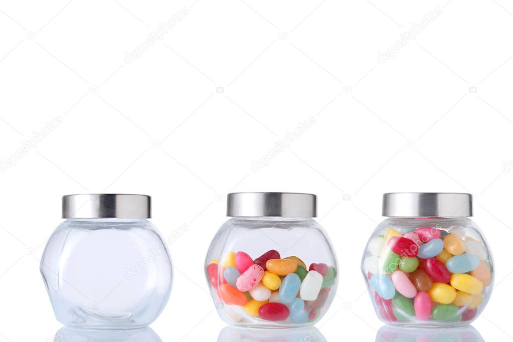 therre glass jar, one empety, one half empty and one full of colored candies isolated on white background with clipping path and copy space for your text