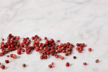 Pembe biber taneleri bir mermer masanın üzerinde duruyor. Metnin için kopyalama alanı var.