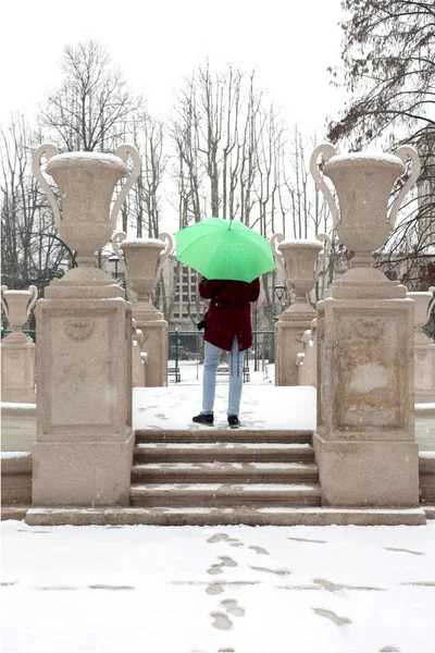 难以辨认的人 在雪天里 他拿着一把开着的雨伞在城市公园里 — 图库照片