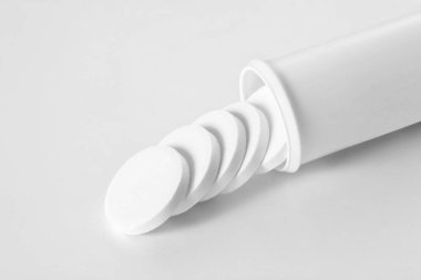 Aspirin tableti beyaz zemin üzerinde izole edilmiş tüpünden çıkıyor. Metnin için kopyalama alanı var.