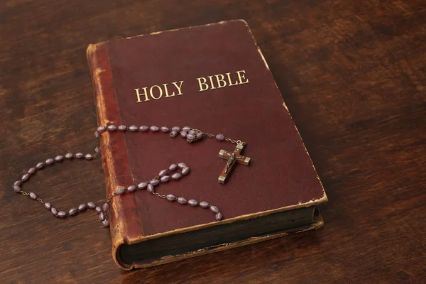 神圣的圣经和一个有念珠的十字架放在一张木制桌子上 上面有抄写你的文字的地方 — 图库照片