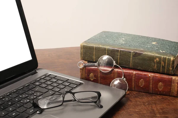 personal computer and old books with ancient and moder reading glasses on a wooden table with copy space for your text