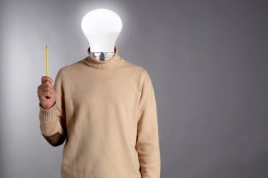 Komik bir fikir: lambalı soyut bir adam kafasının yerine, elinde bir kalem ve gri arkaplanda, metin alanınız için fotokopi alanı var.