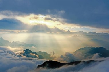 sunshine through cloud on mountain peak clipart