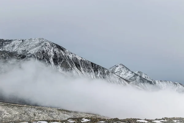 snow on mountain peak in cloud