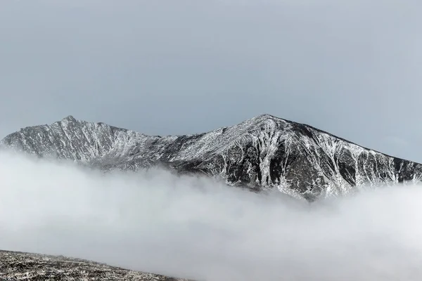 snow on mountain peak in cloud