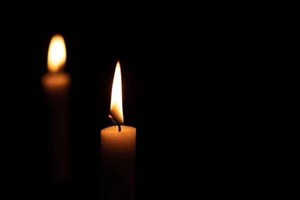 Two isolated burning yellow candles in the dark — Stock Photo, Image