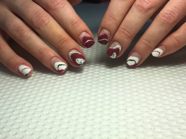 Kırmızı desenli ve beyaz noktalı şık bir manikür.