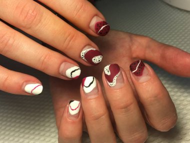 Kırmızı desenli ve beyaz noktalı şık bir manikür.
