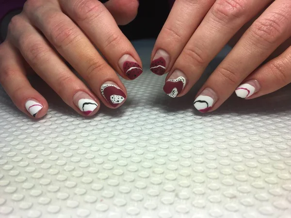 Manicura de moda y elegante con un diseño rojo y puntos blancos —  Fotos de Stock